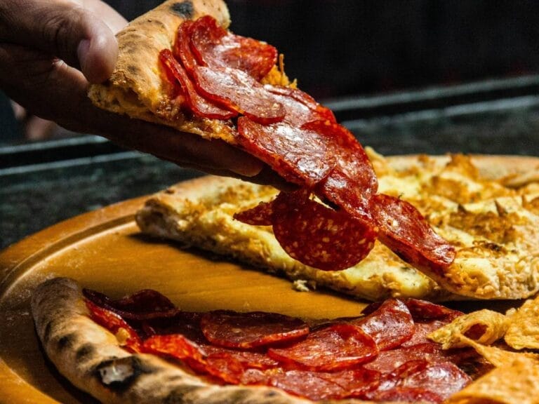 Drewniany talerz z pizzą. Obrazek w artykule Ile kcal ma kawałek pizzy? Kaloryczność pizzy w popularnych rozmiarach.