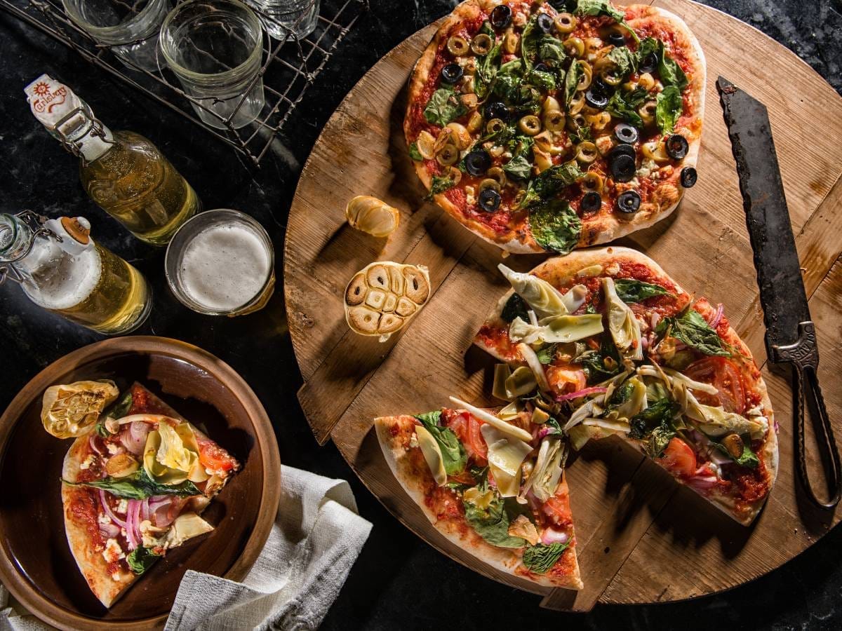 Pizza i składniki na stole. Obrazek w artykule Karczochy pizza - jak przygotować pyszną i zdrową włoską pizzę?