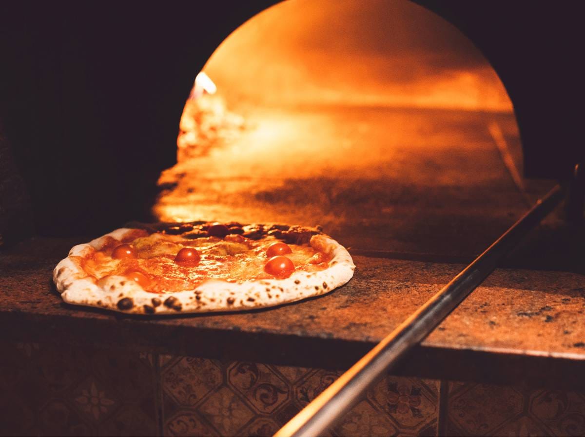 Piec do pizzy i wkładana pizza. Obrazek w artykule W jakiej temperaturze piec pizzę? Poradnik dla początkujących.