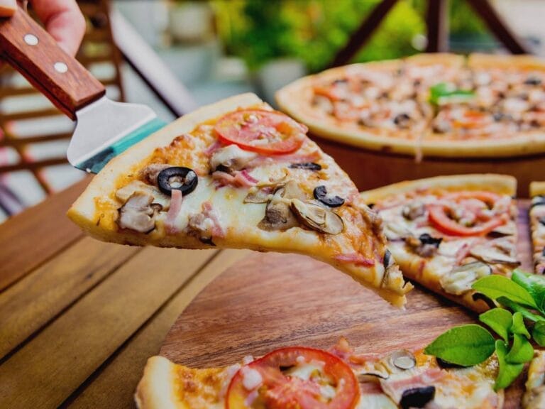 Pizza w kawałkach na drewnianym talerzu. Obrazek w artykule Pizza 40 cm - na ile osób warto zamówić taką pizzę?