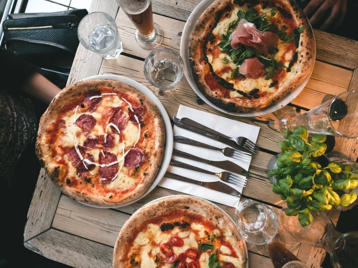 Stół z pizzami. Obrazek w artykule Pizza Leszno - gdzie zjeść najlepszą pizzę w mieście?