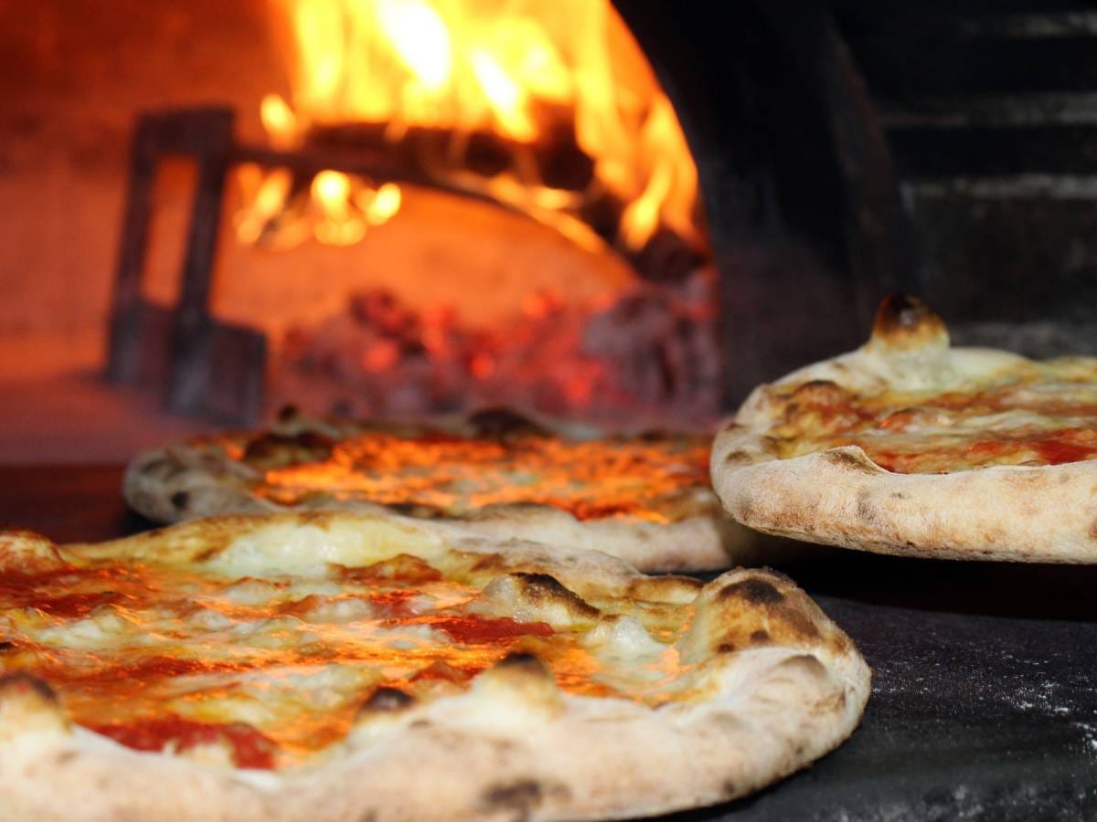 Pizza na tle pieca w pizzerii. Obrazek w artykule Sieci pizzerii w Polsce. Ranking i analiza popularnych marek.