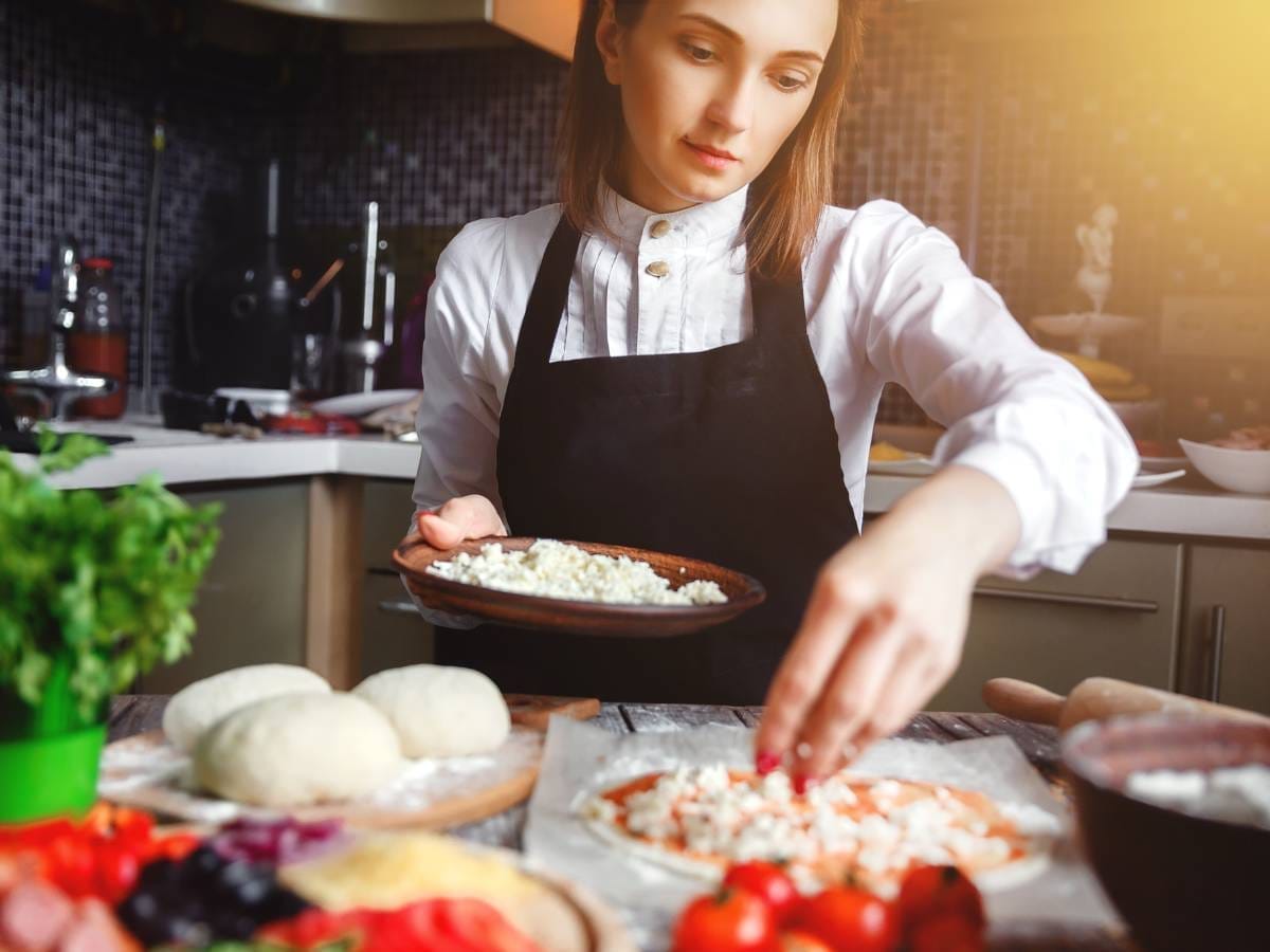 Dziewczyna przy robieniu pizzy Obrazek w artykule Jaki sos na pizze? Jak zrobić najlepszy sos do pizzy w domu?