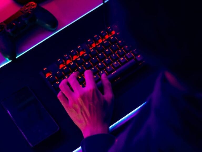 Ręce gracza na klawiaturze. Obrazek w artykule Idealny sprzęt komputerowy dla graczy komputerowych. Jak wybrać najlepszy sprzęt dla swoich potrzeb?